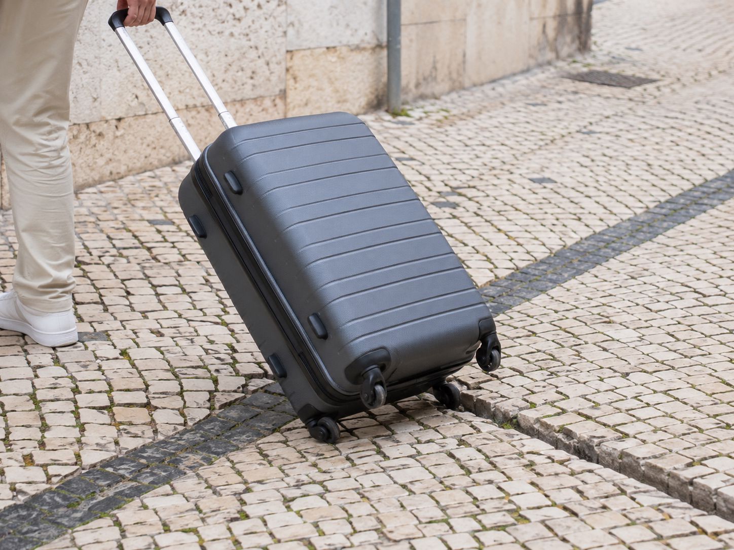Trolley sobre calçada portuguesa, ilustrando a importância de escolher rodas adequadas para viagens urbanas.