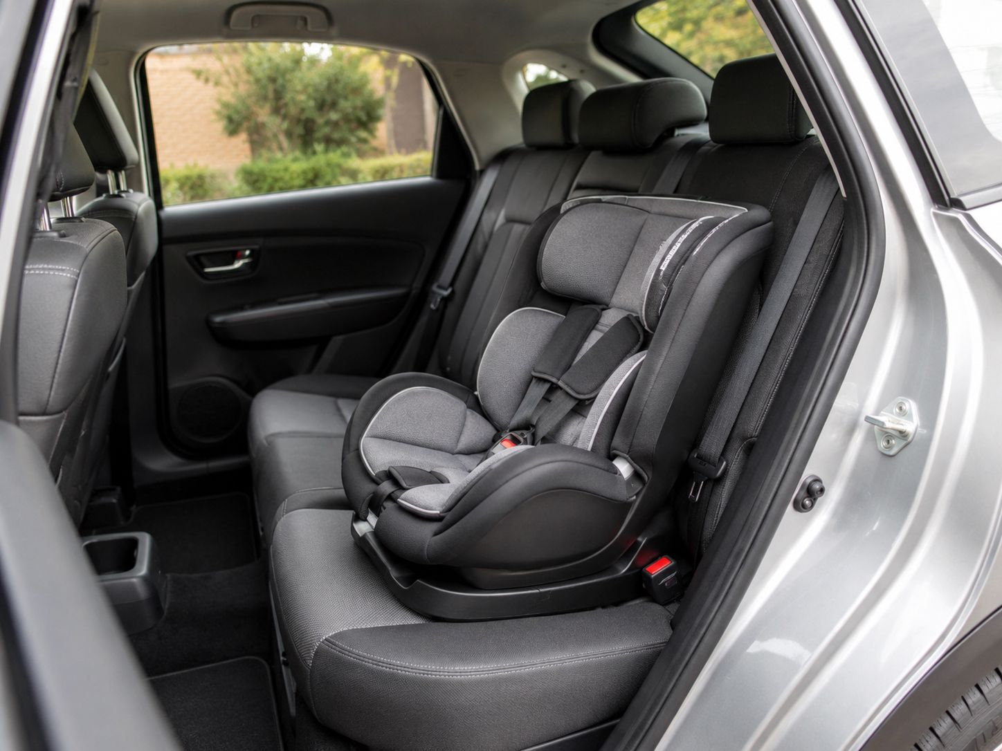Cadeira auto infantil instalada no banco traseiro de um carro, representando a importância da segurança, compatibilidade e instalação correta.