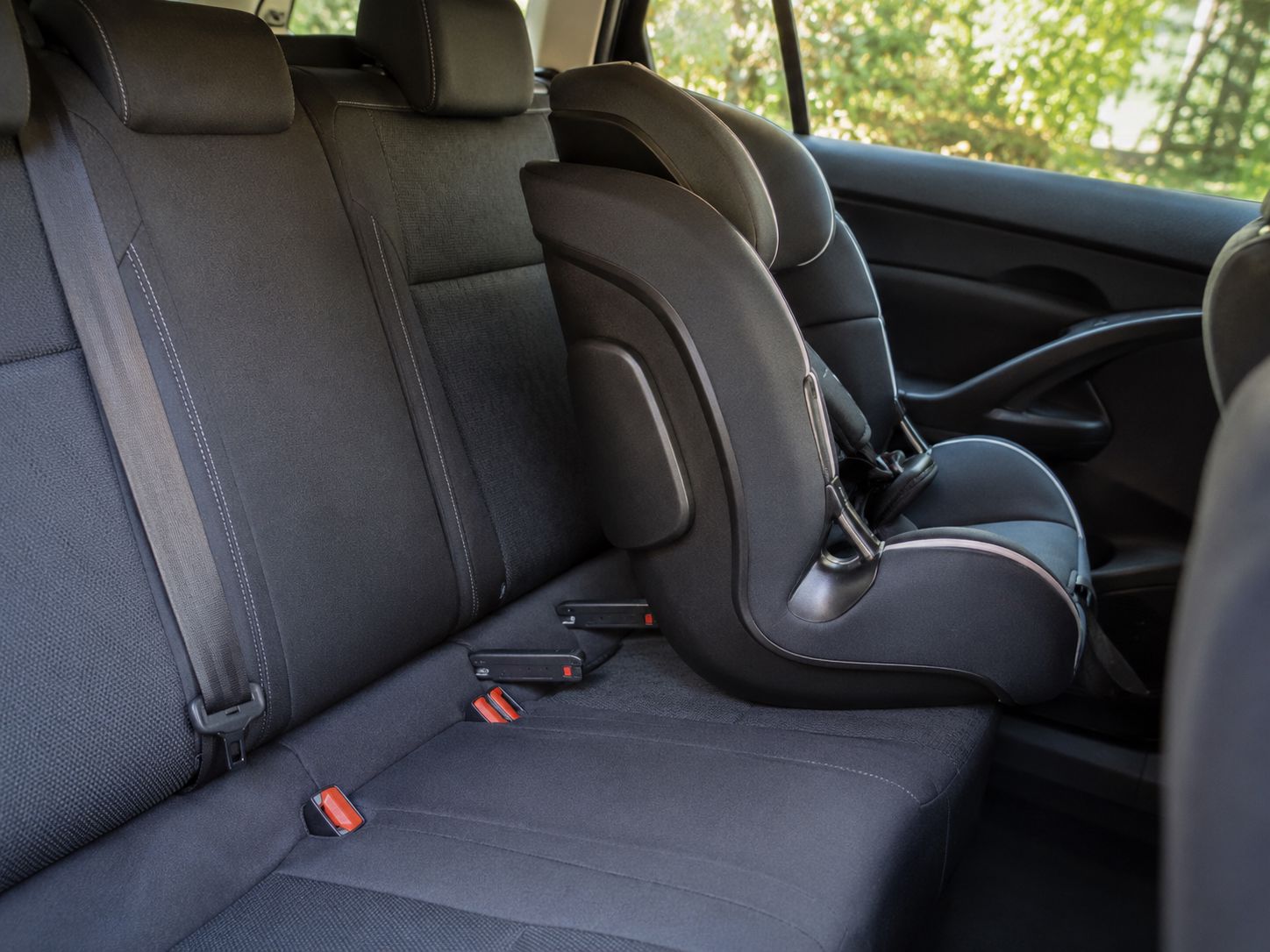 Cadeira auto alinhada no banco traseiro de um carro com pontos ISOFIX visíveis, representando a importância da instalação correta.